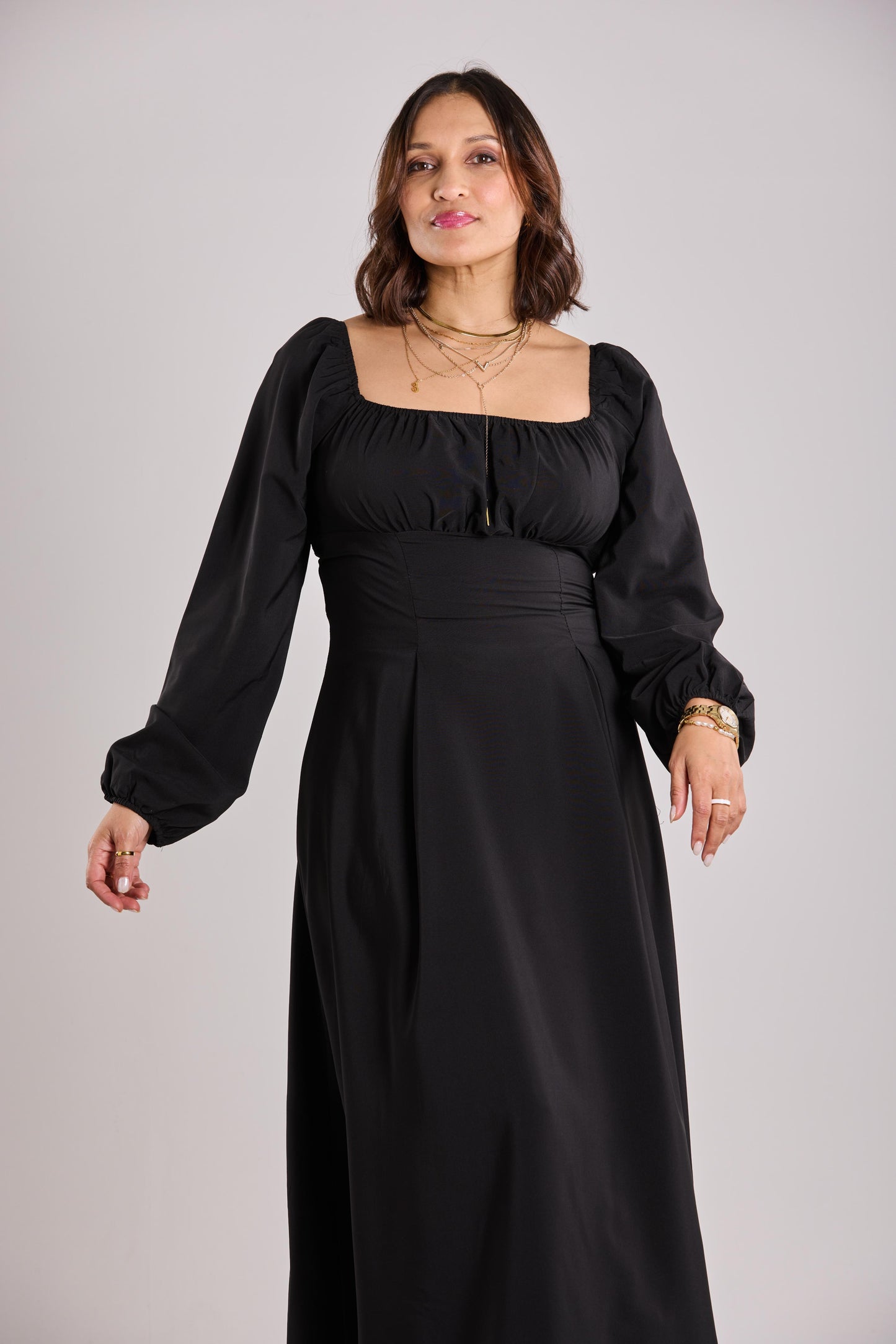 Woman wearing a black dress with long sleeves on a gray background