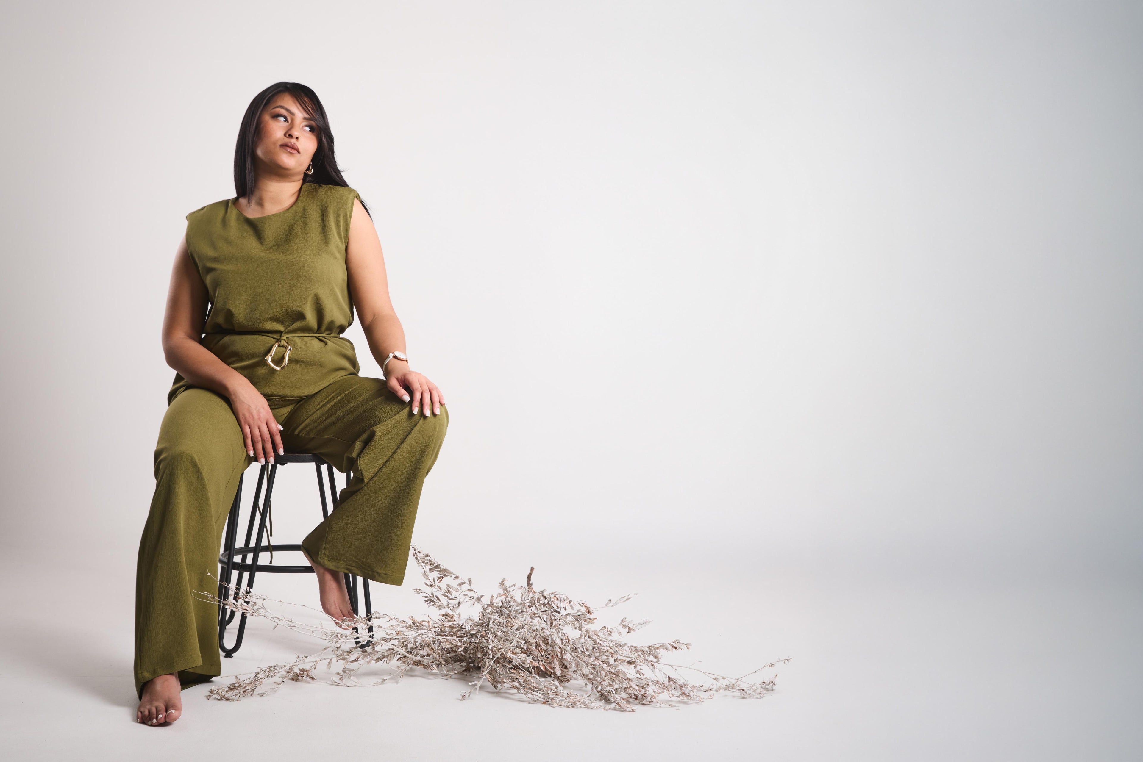model in green outfit siting stylish on chair